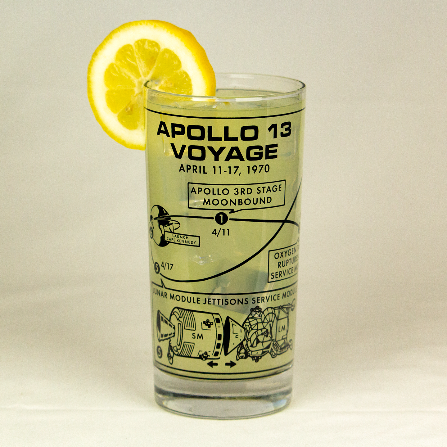 Vintage style glassware with Apollo 13 Voyage design and lemon slice on a beige background