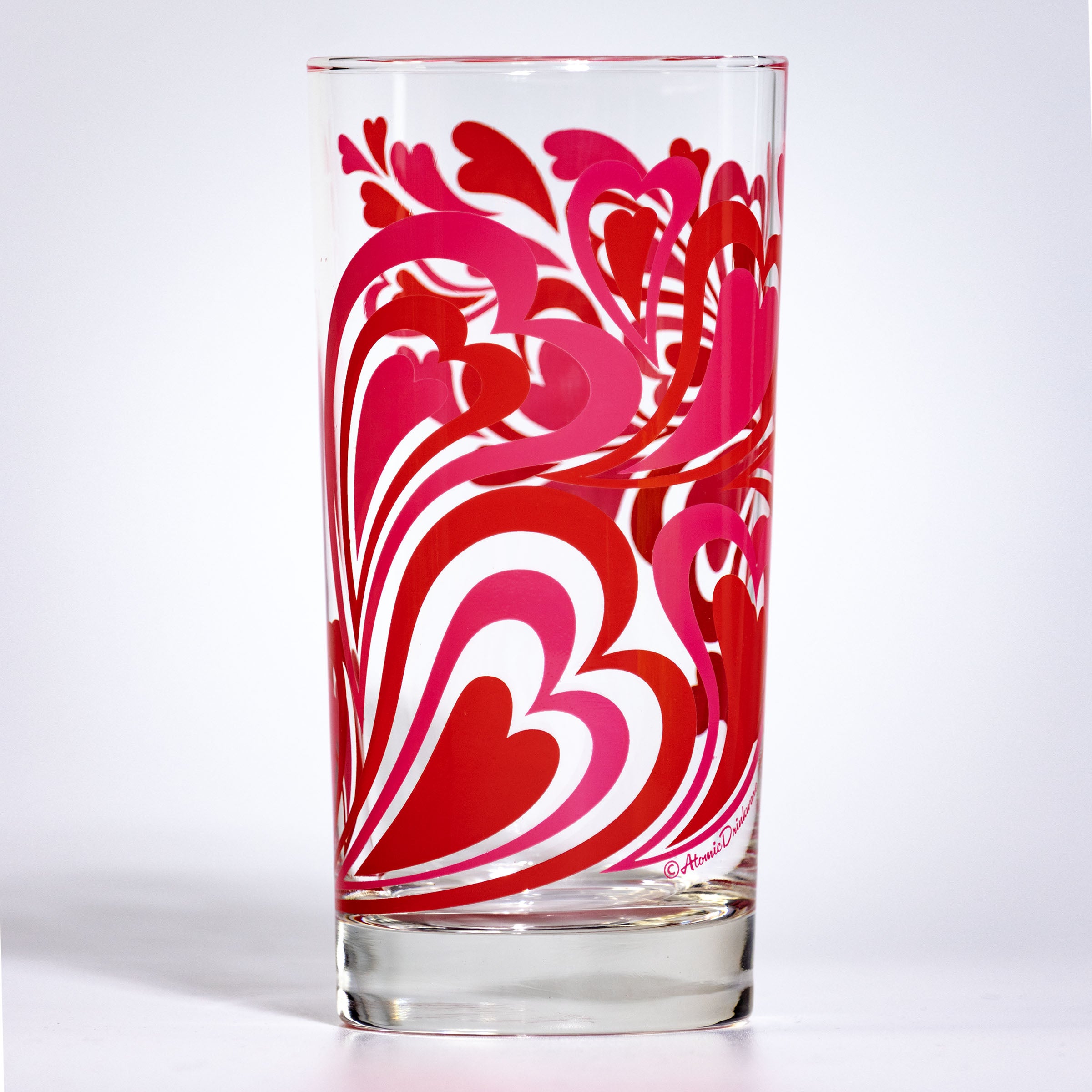 Glass tumbler with pink and red retro heart pattern on a white background