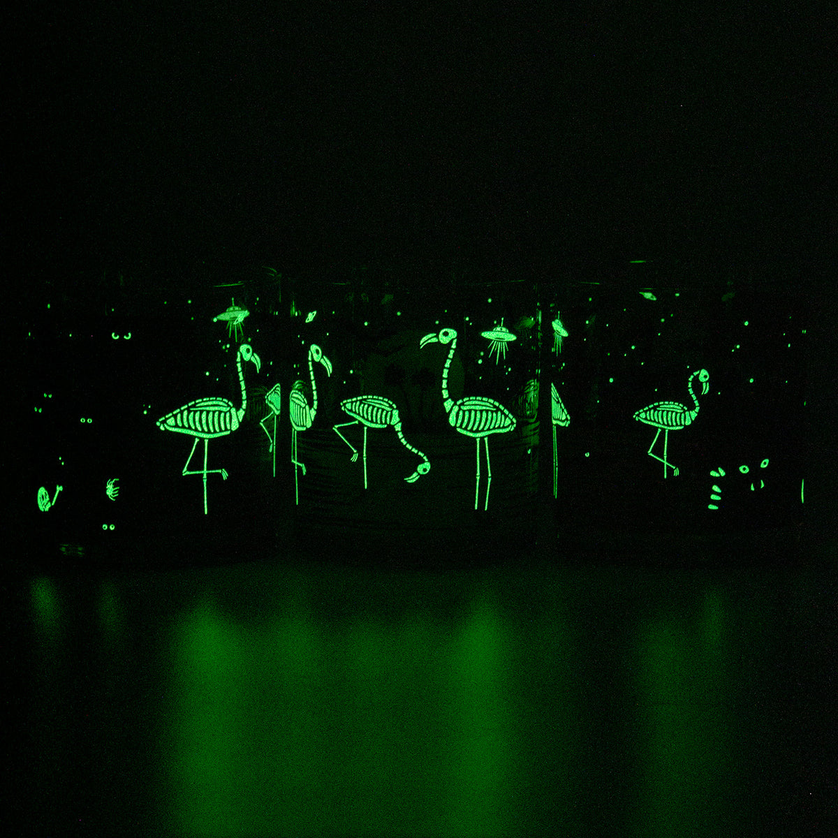 3 Glow in the dark Eerie Everglades Rocks glasses glowing green in the dark to show off the skelemingo illumination. 