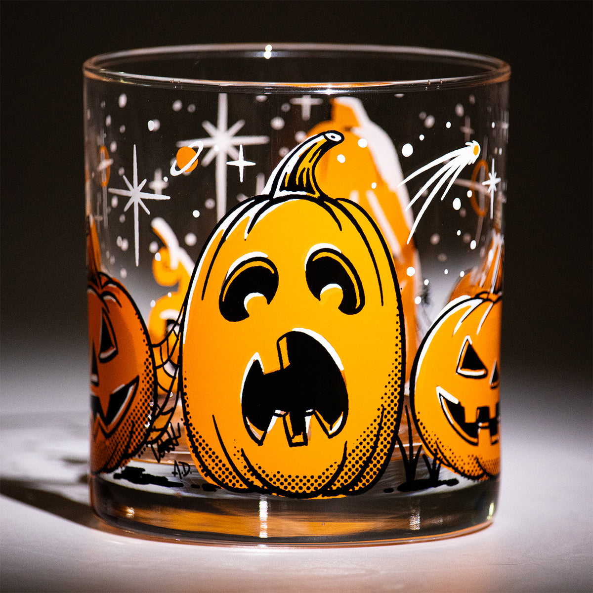 Five Little Pumpkins Rocks glass with retro style hand illustrated jack-o-lantern with shooting stars on a dark background. Tall surprised Halloween pumpkin 