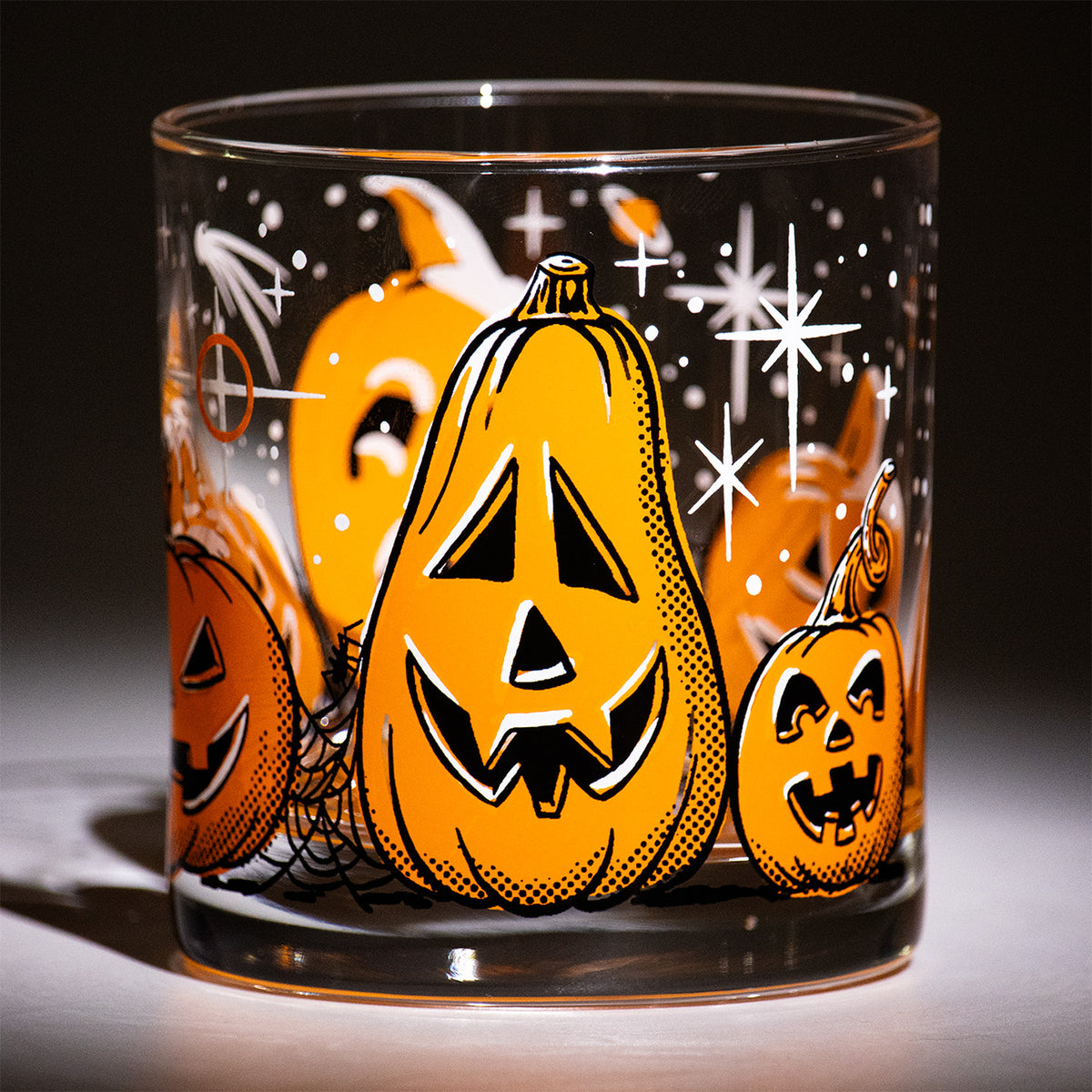 Five Little Pumpkins Rocks glass with retro style hand illustrated jack-o-lantern with shooting stars on a dark background.  Tall Friendly Halloween Pumpkin