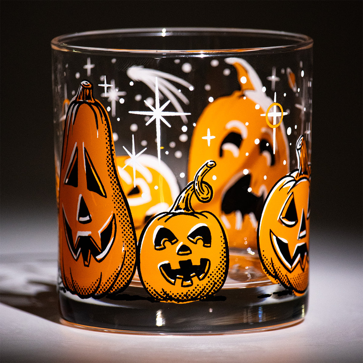 Five Little Pumpkins Rocks glass with retro style hand illustrated jack-o-lantern with shooting stars on a dark background.  Baby Halloween pumpkin with curly stem