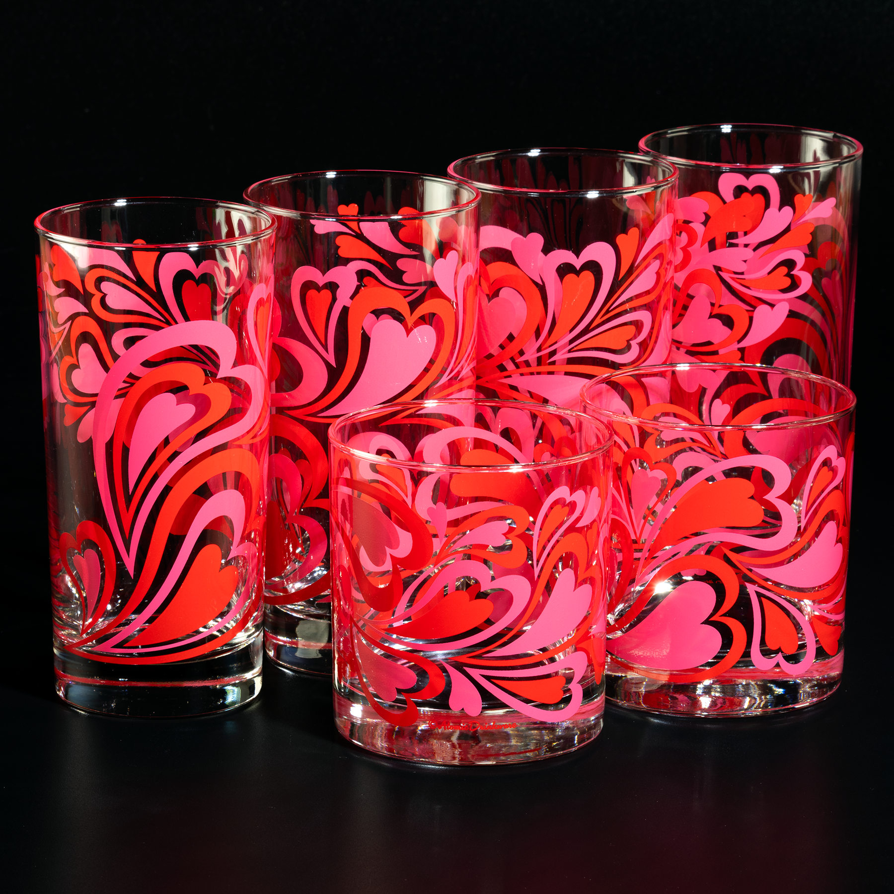 Set of six glass tumblers with pink and red floral patterns on a black background