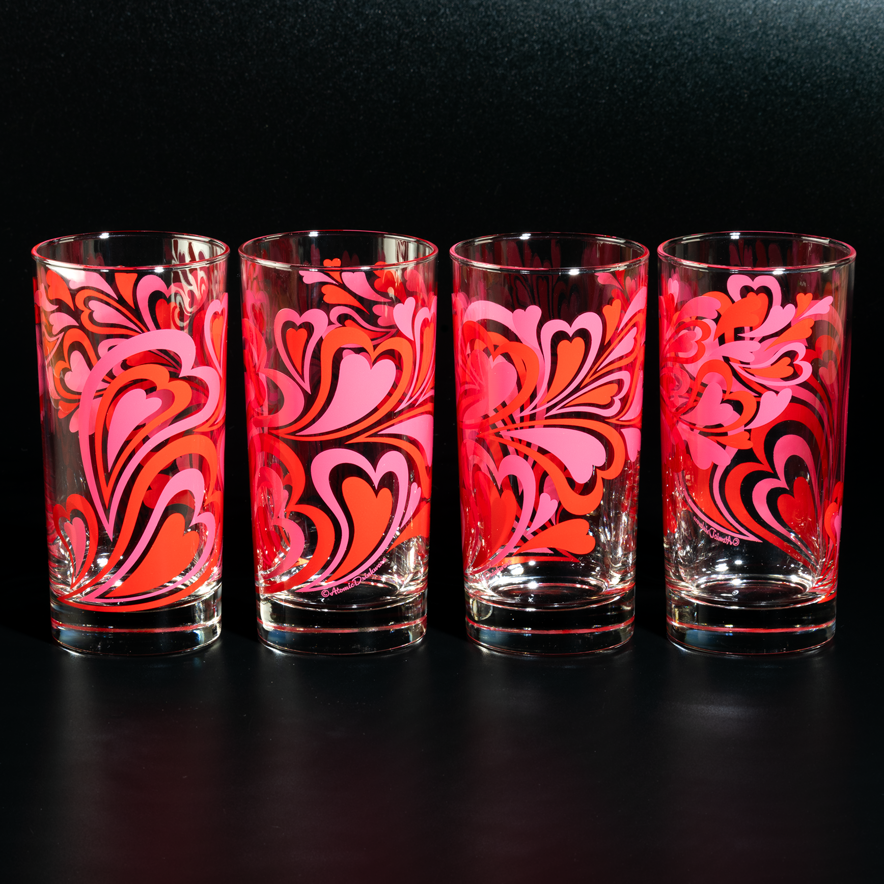 Glass tumbler with pink and red retro heart pattern on a white background