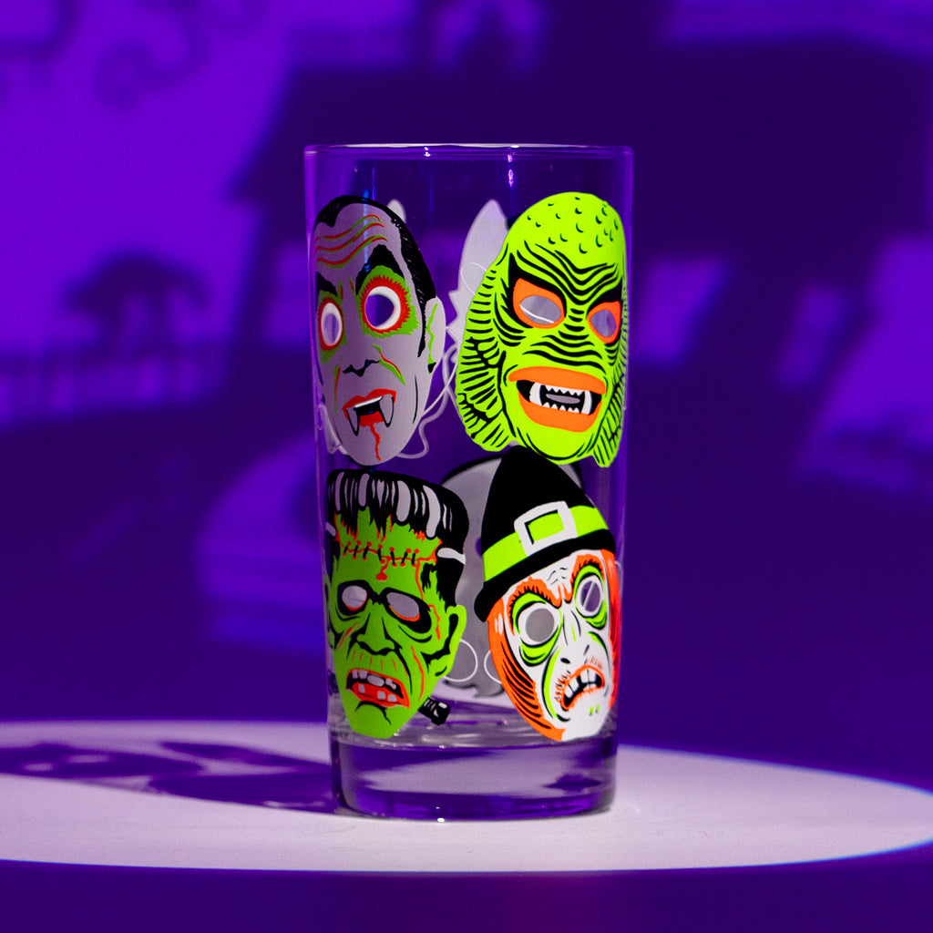 Single Neon Nightmares glass with screen printed retro monster masks. Shadowy purple background.