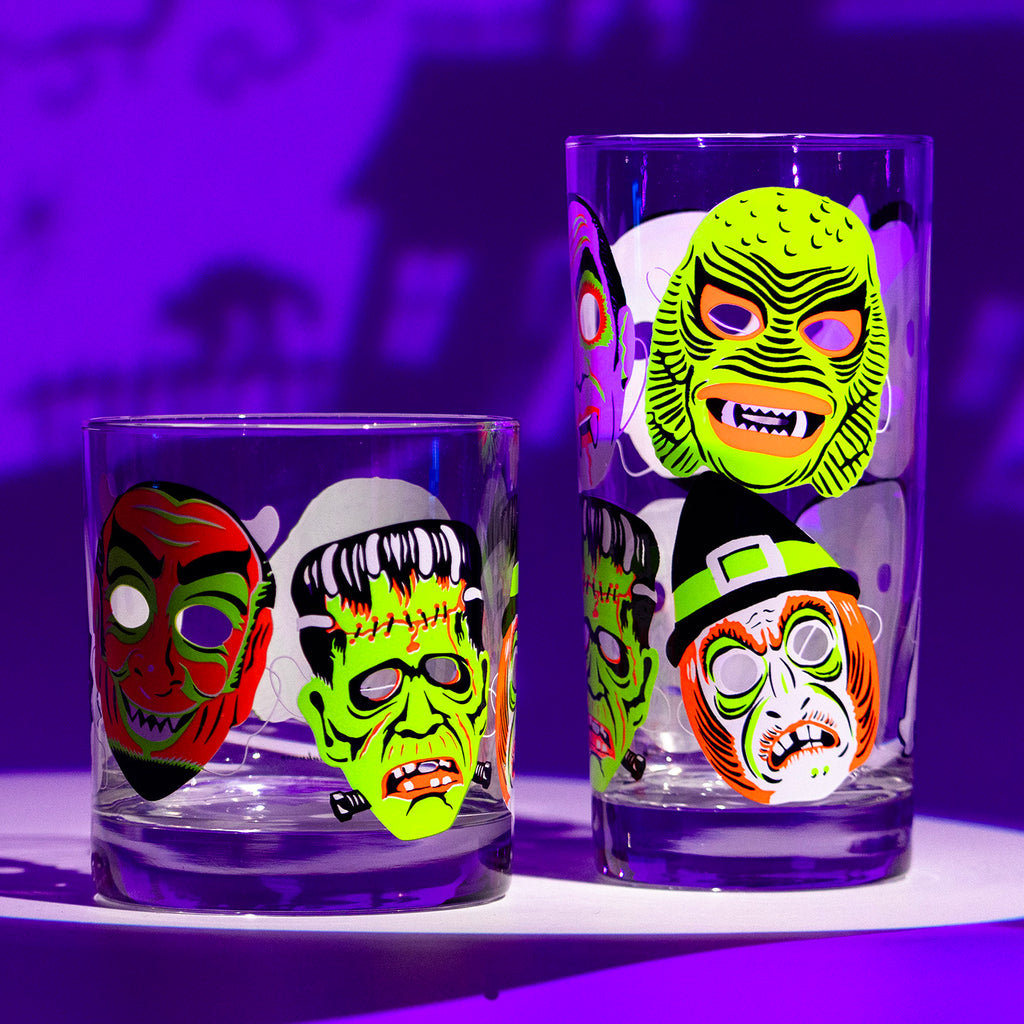 A collins and rocks glass in the Neon Nightmare design with screen printed retro monster masks on a spooky purple background.