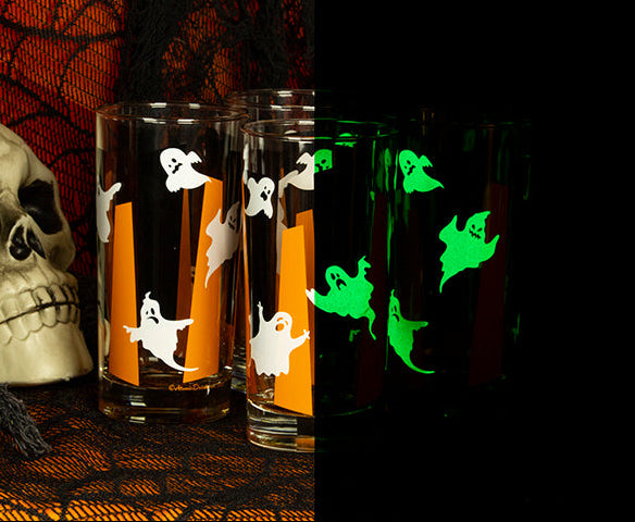 Split view of Glowing Ghouls collins drinkware in light and glowing in the dark on an orange and black netting background