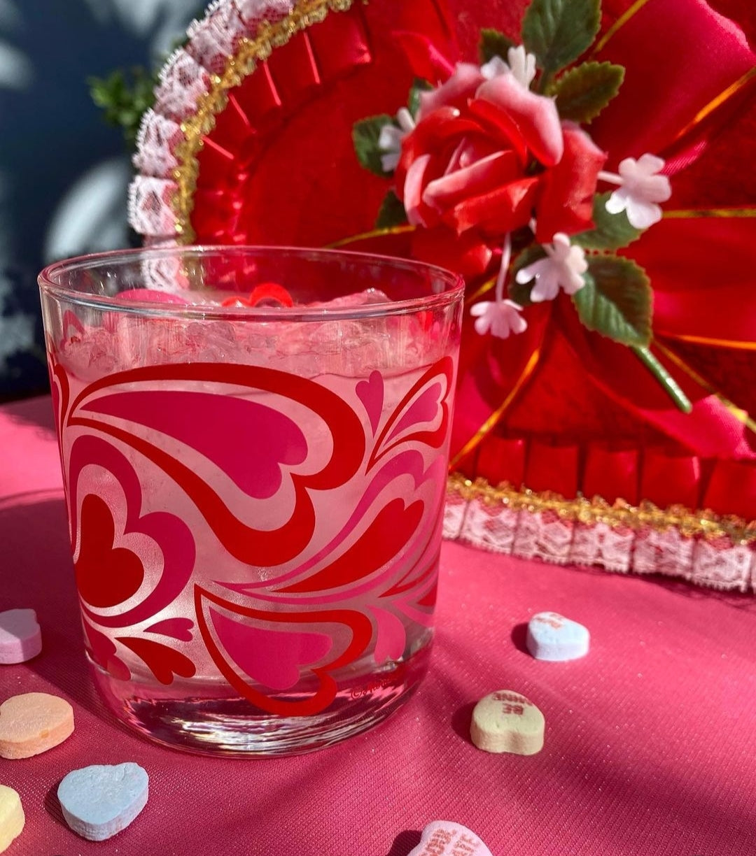Glass with heart design on a pink surface with decorative elements