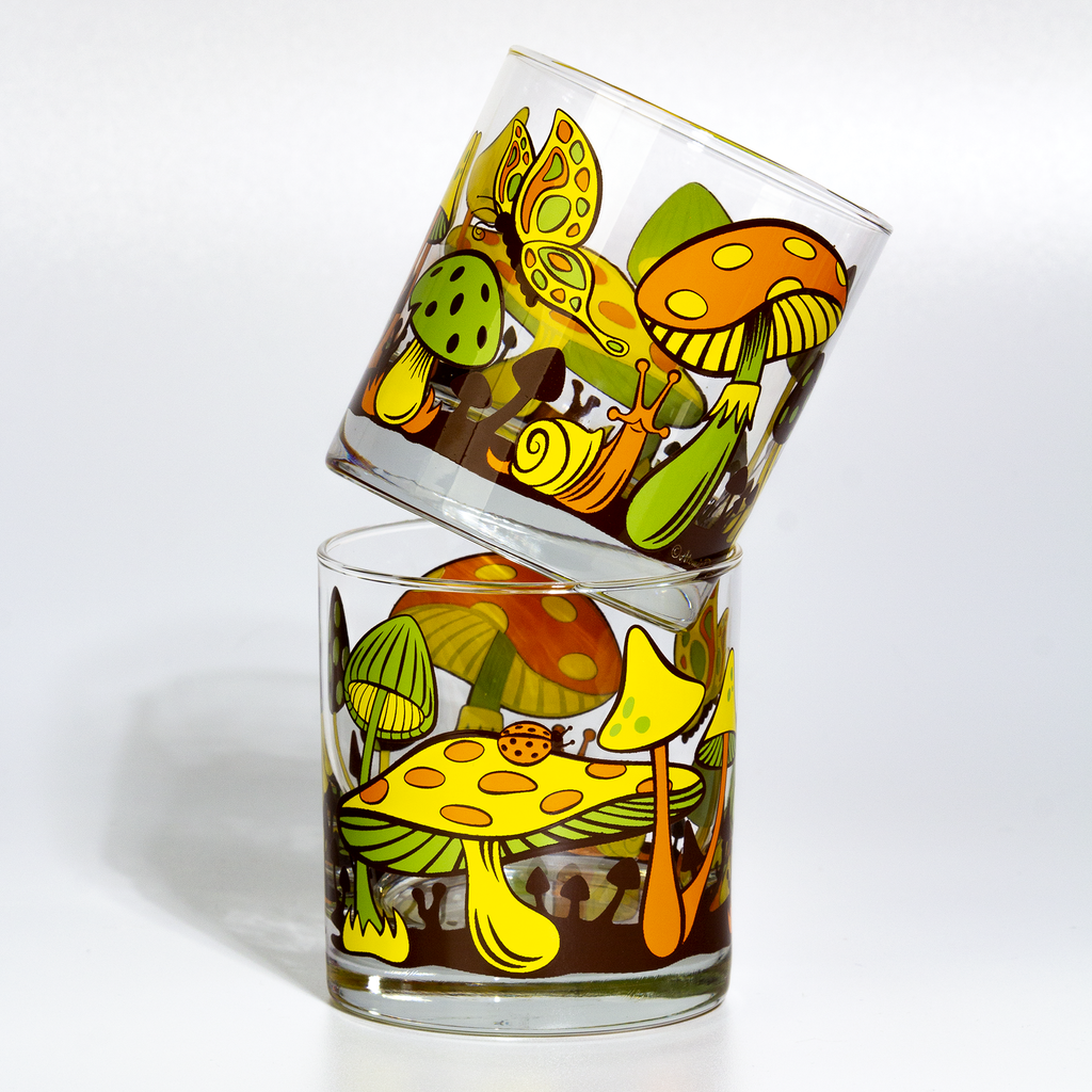 Two glass tumblers with colorful retro mushroom design on a white background