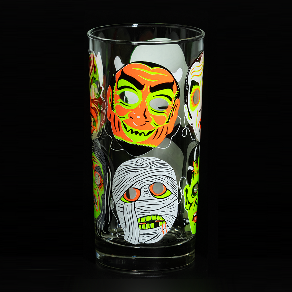 Clear Collins glass on black background, showing fluorescent green and orange retro Halloween mummy and devil mask