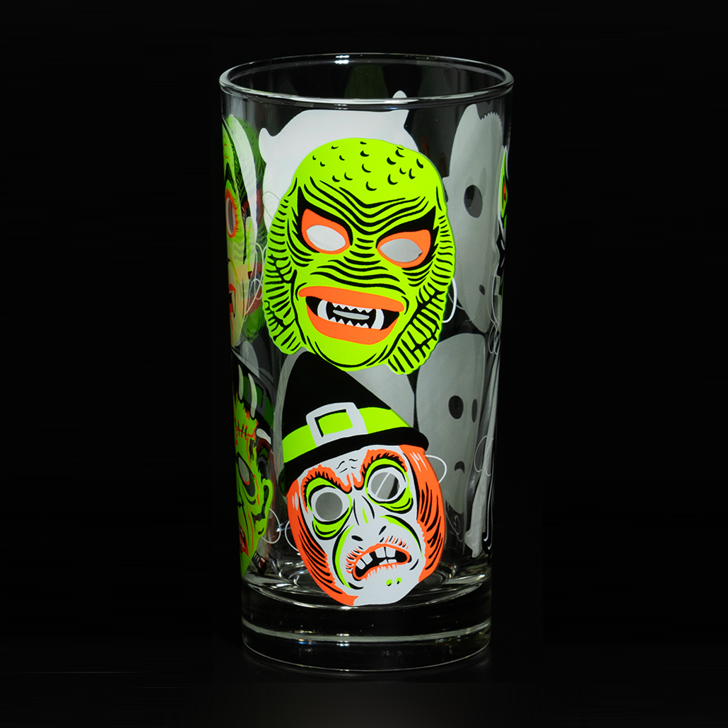 Clear Collins glass on black background, showing fluorescent green and orange retro Halloween The Creature swamp thing and hag witch mask