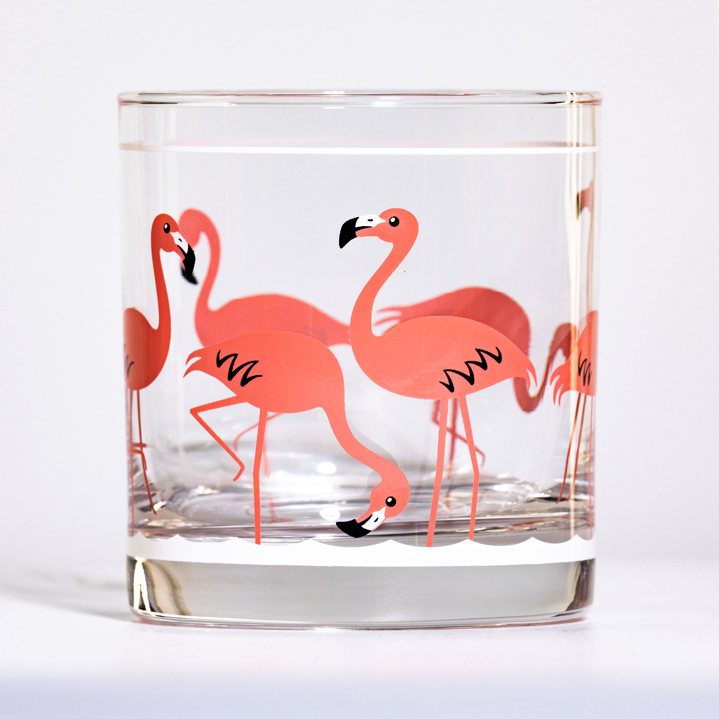 Clear glass tumbler with retro pink flamingo design on a white background