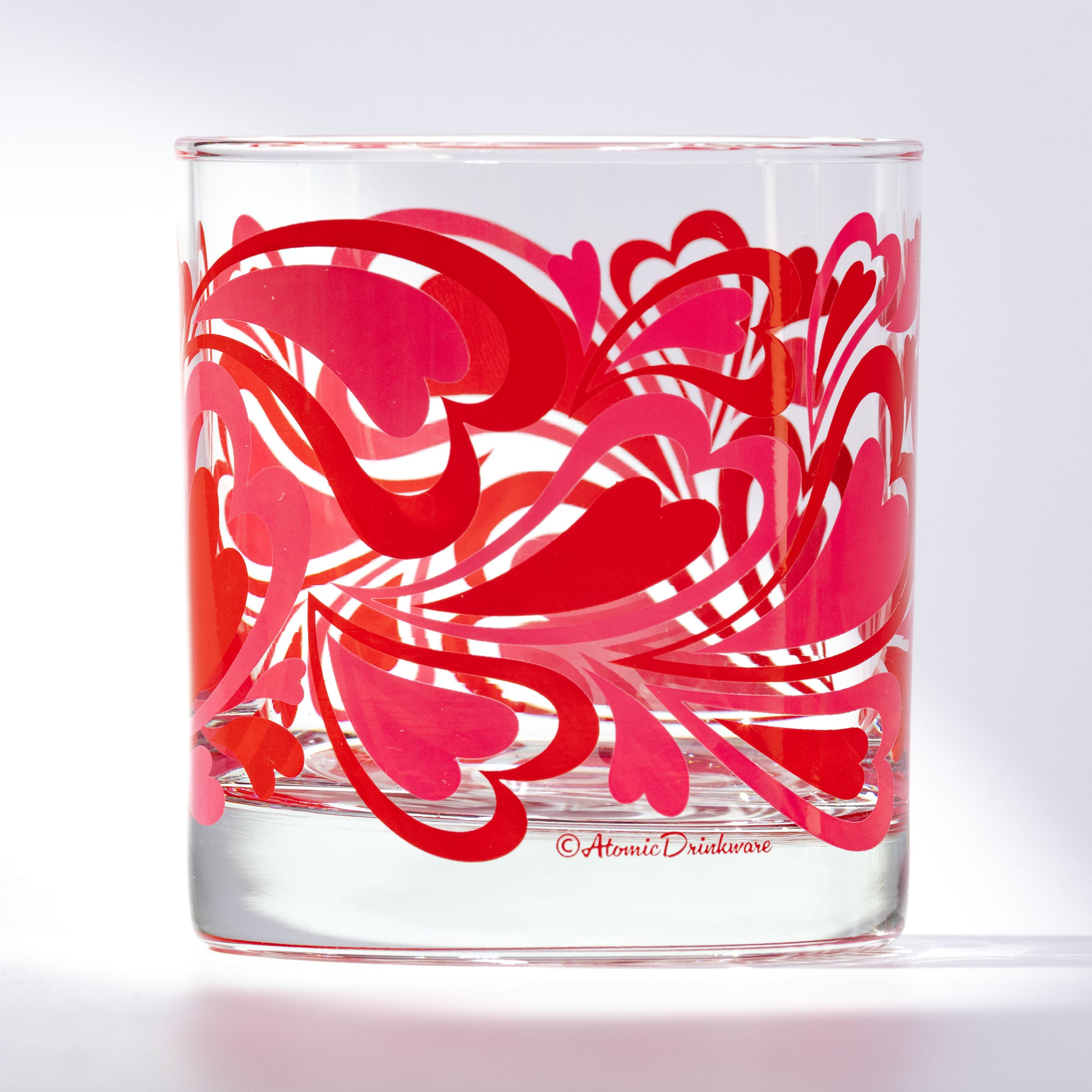 Clear glass tumbler with pink floral design on a white background