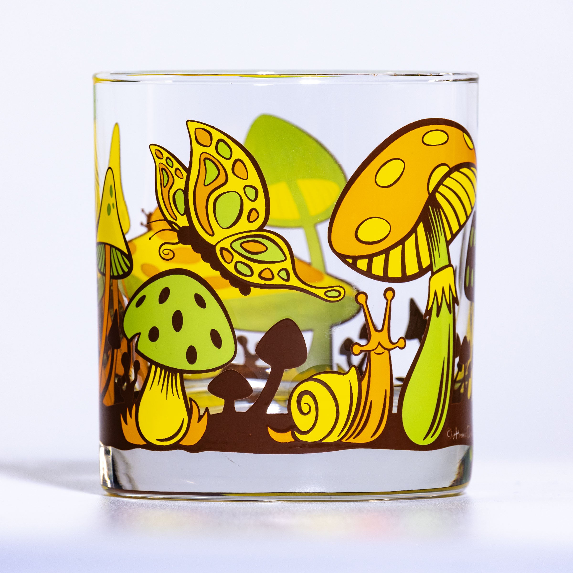 Glass with colorful mushroom and butterfly design on a white background