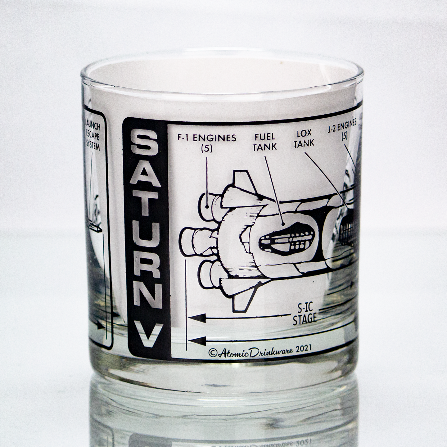 Clear glass tumbler with Saturn V rocket design and text on a white background