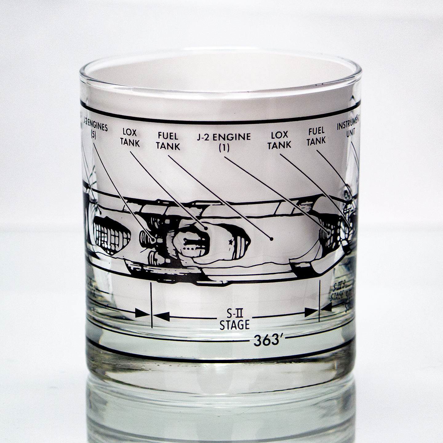 Glass tumbler with rocket engine design etched on it against a white background