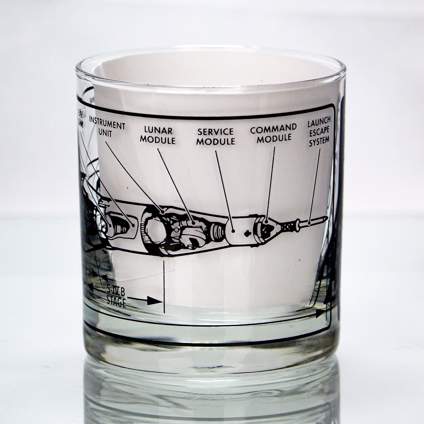 Glass tumbler with rocket diagram etched on it against a white background