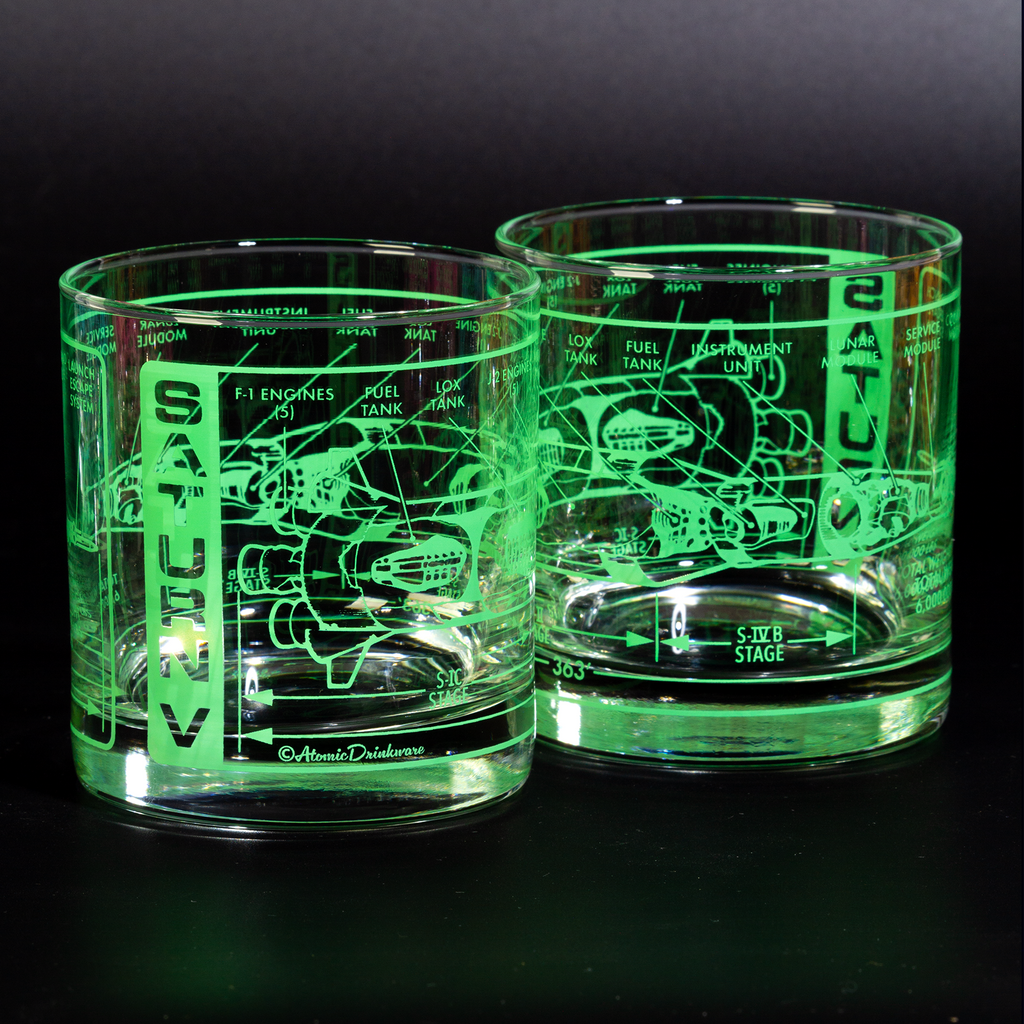 Two glass tumblers with engraved designs on a black background