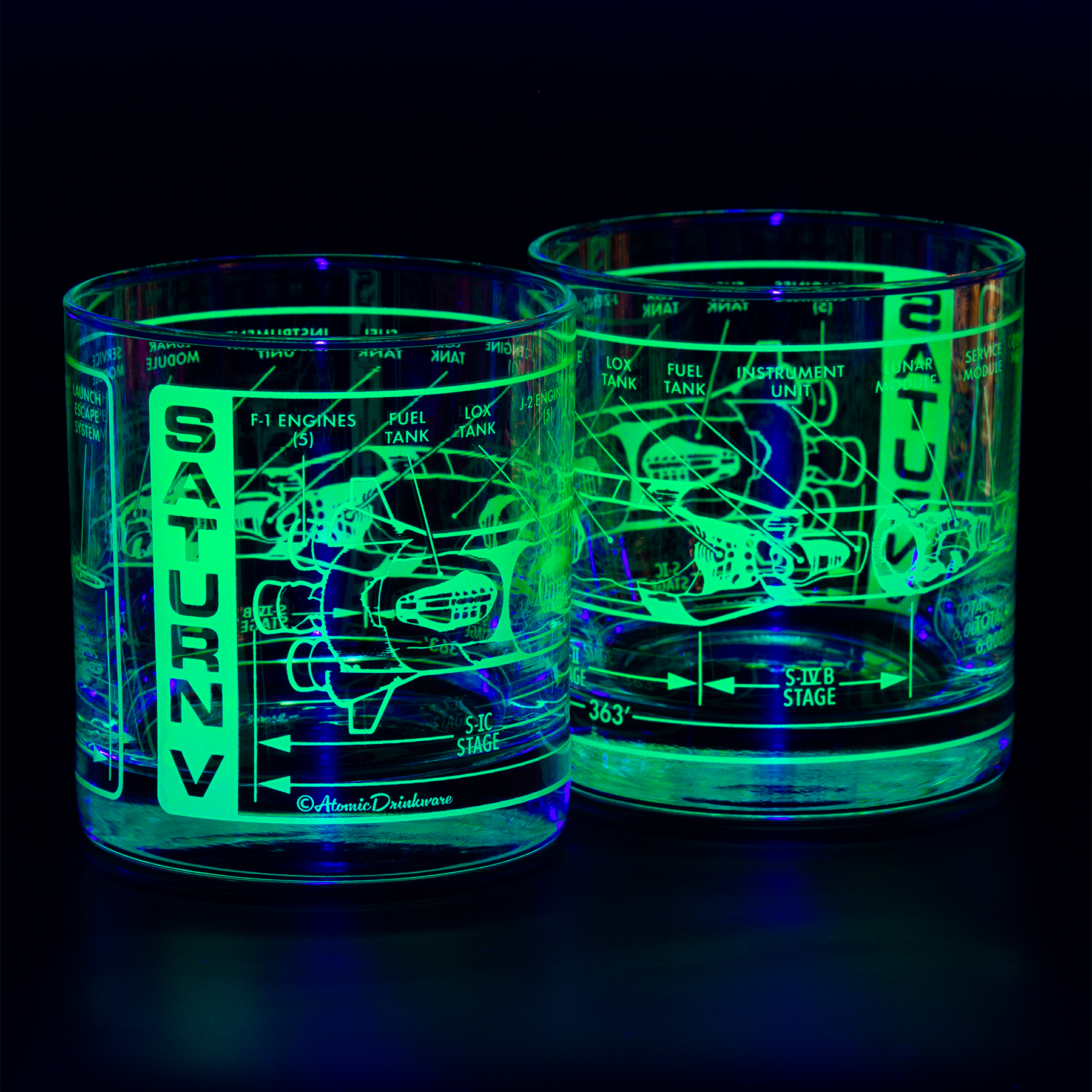 Two glowing glass tumblers with detailed etchings on a black background