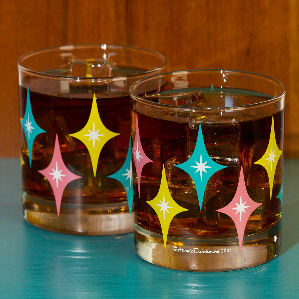 Two glasses with retro star pattern filled with a dark liquid on a blue surface.