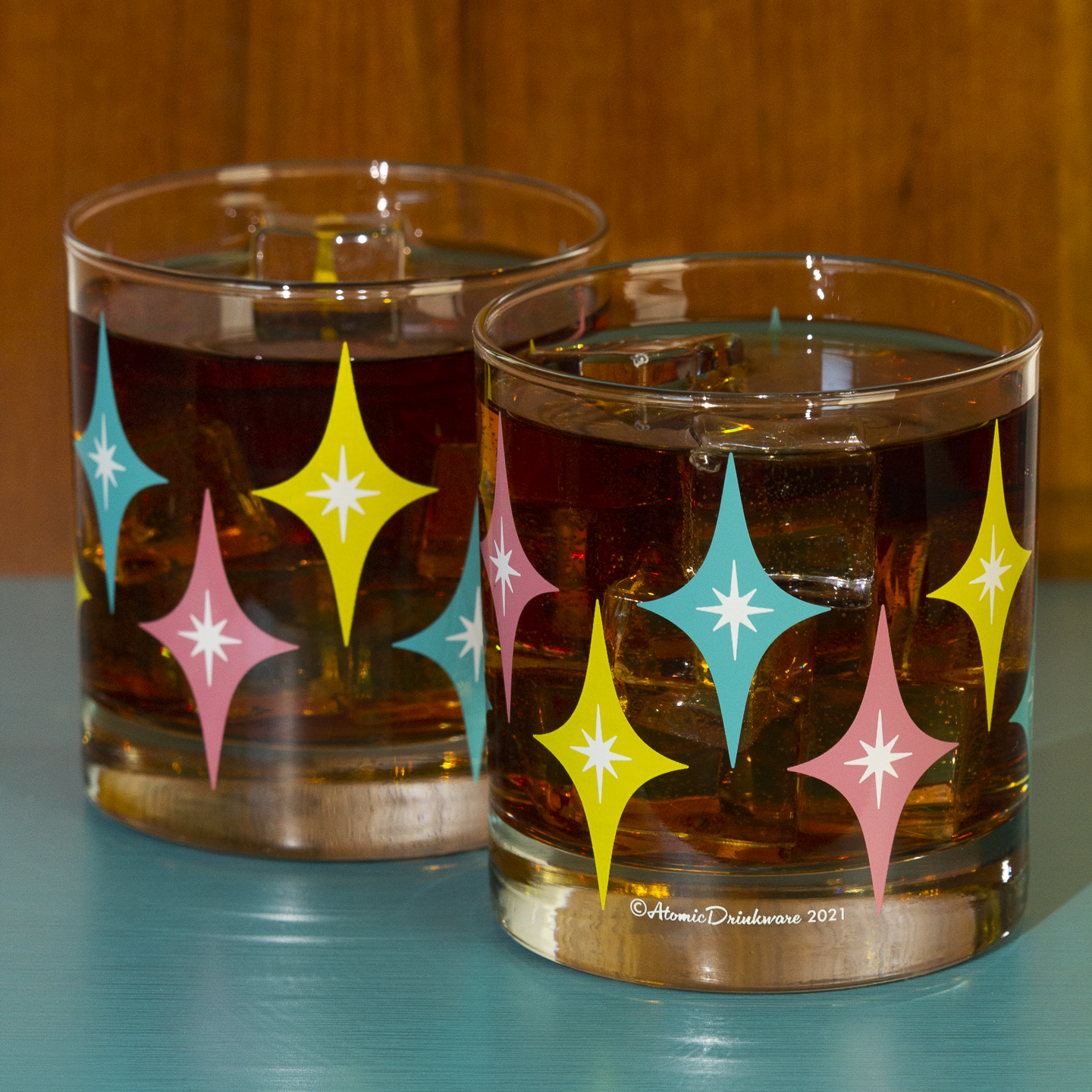 Two glasses with retro star pattern filled with a dark liquid on a blue surface.