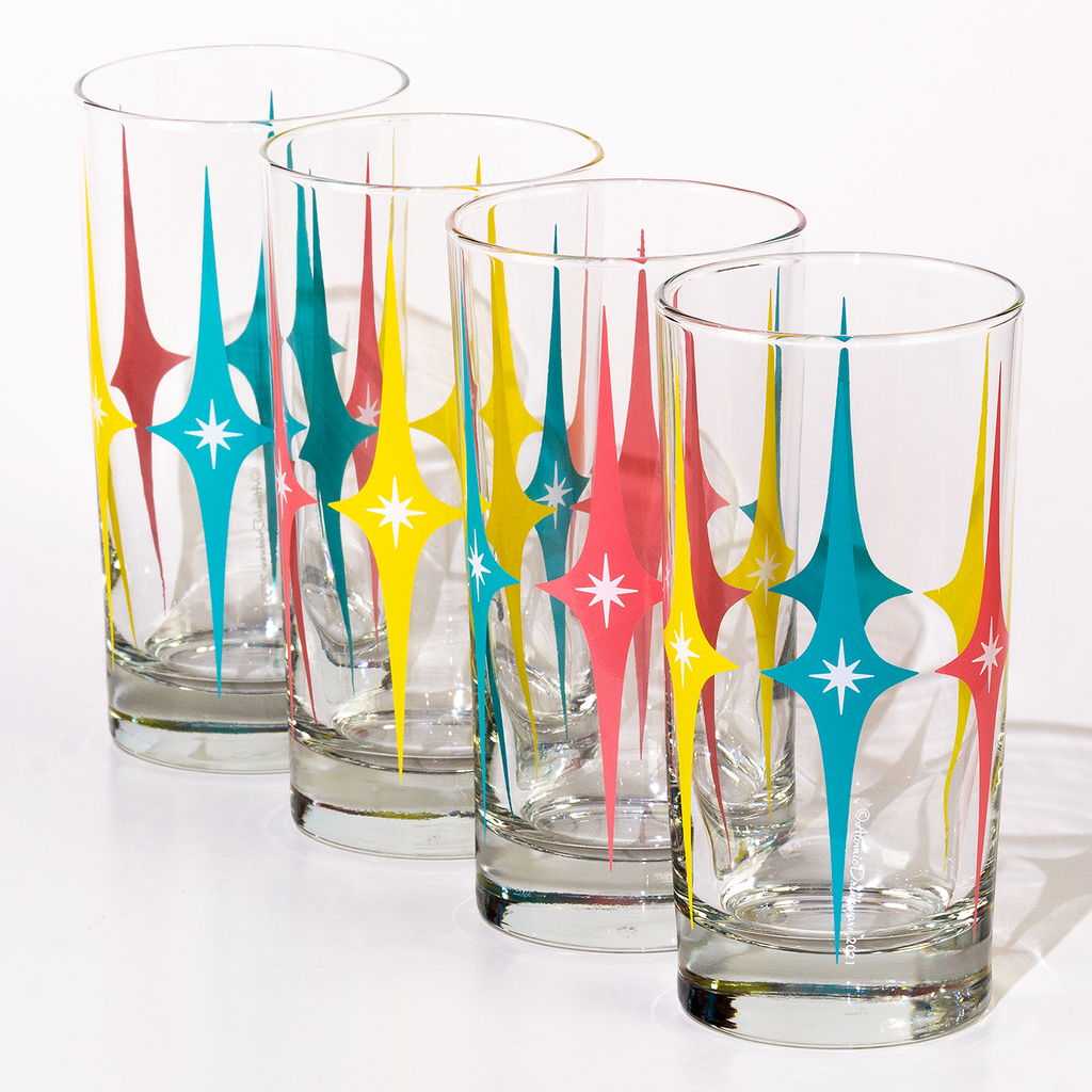 Set of four glass tumblers with colorful retro starburst designs for home barware or collectors item