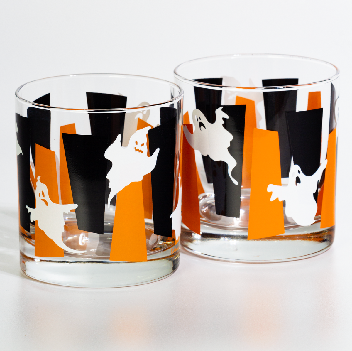 Two clear glass rocks with a Halloween pattern of black and orange googies and white glow in the dark ghosts, shown on a white background.