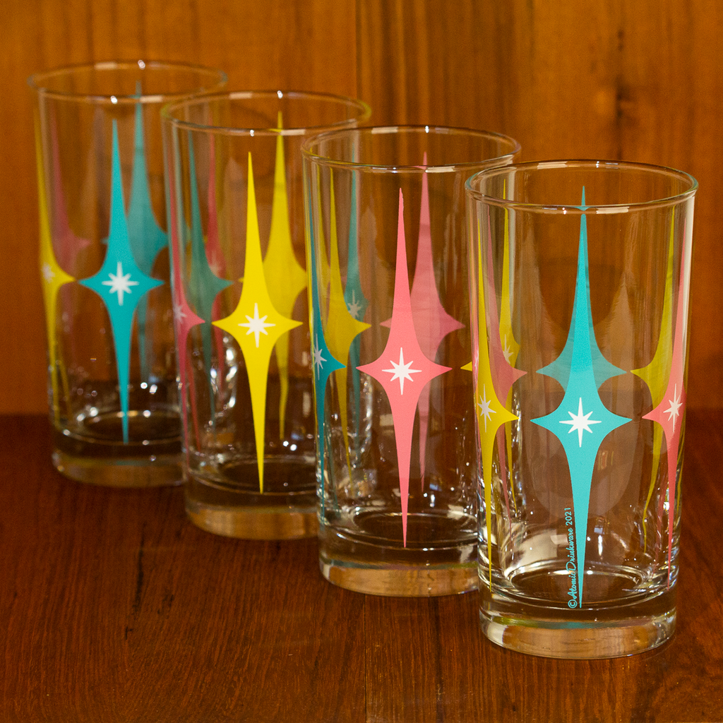 Four glass tumblers with colorful retro geometric designs on a wooden surface