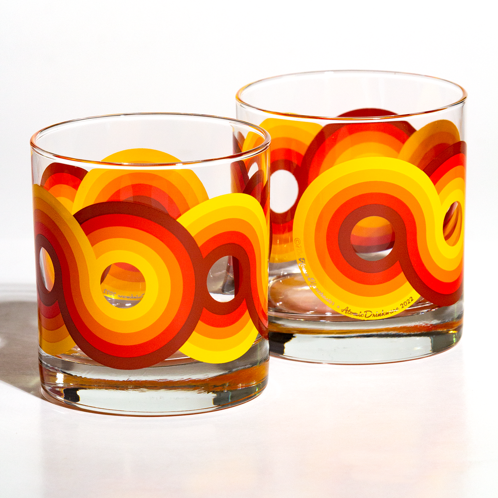 Two glass retro tumblers with colorful circular pattern on a white background