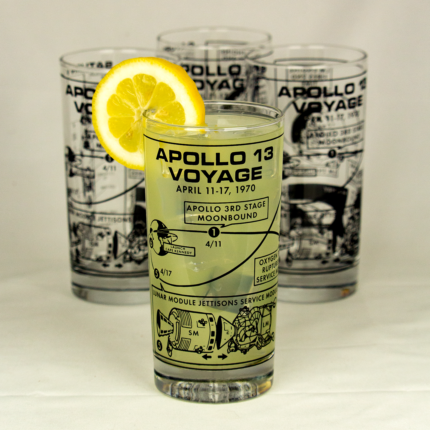 Glass with 'Apollo 13 Voyage' design featuring a lemon slice, on a light background.