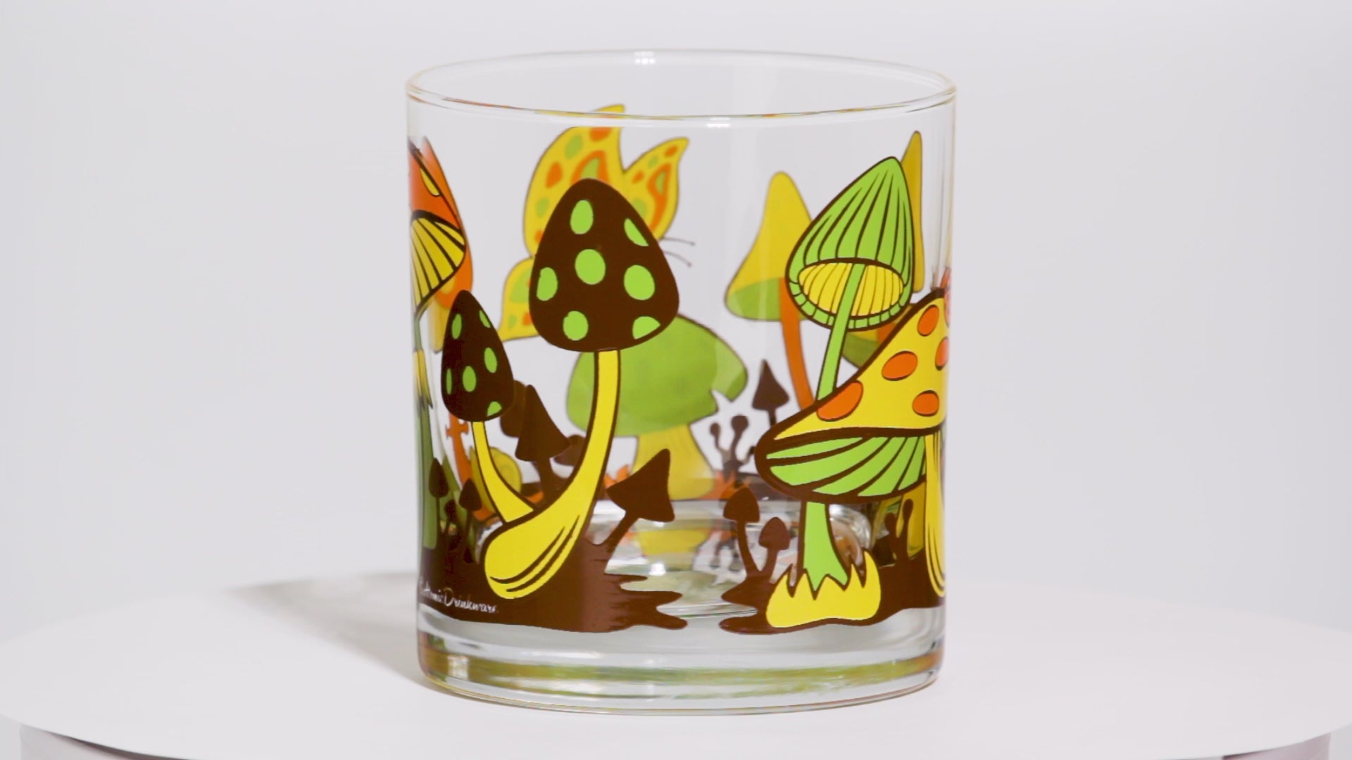 glass tumbler with colorful retro mushroom design on a white background