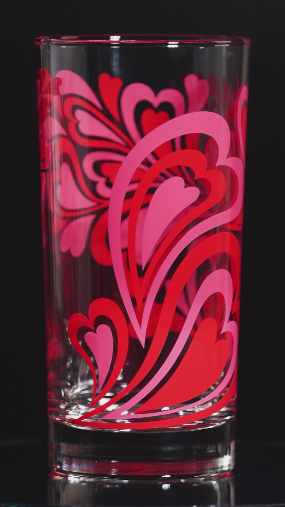 Glass tumbler with pink and red retro heart pattern on a white background