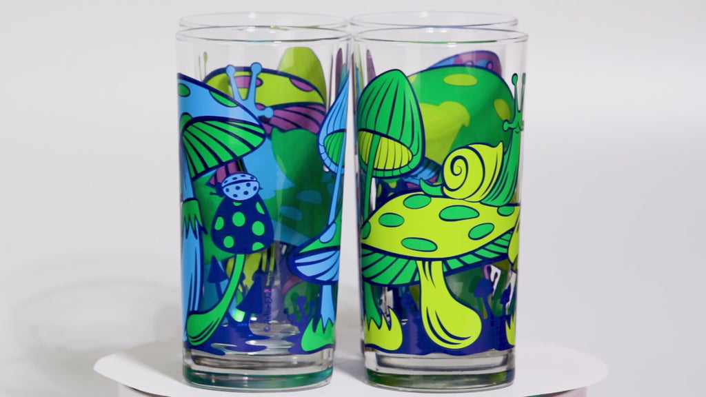 Set of colorful glass tumblers with retro mushroom and abstract designs on a white background