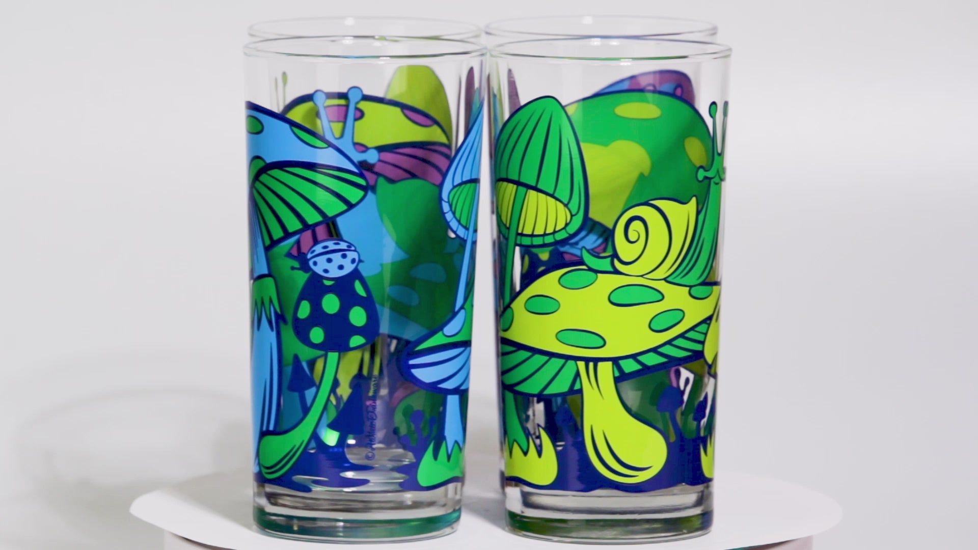 Set of colorful glass tumblers with retro mushroom and abstract designs on a white background
