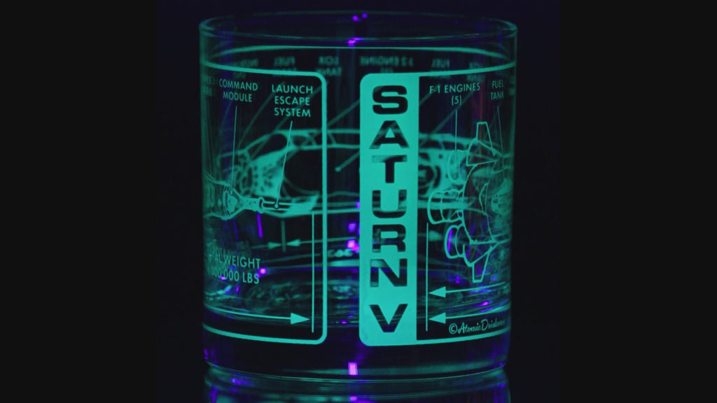 glass tumbler with engraved Saturn V rocket design on a black background