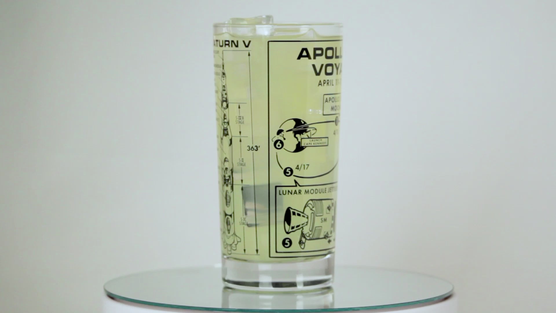 Glass with Apollo 13 Voyage design and lemon slice on a beige background
