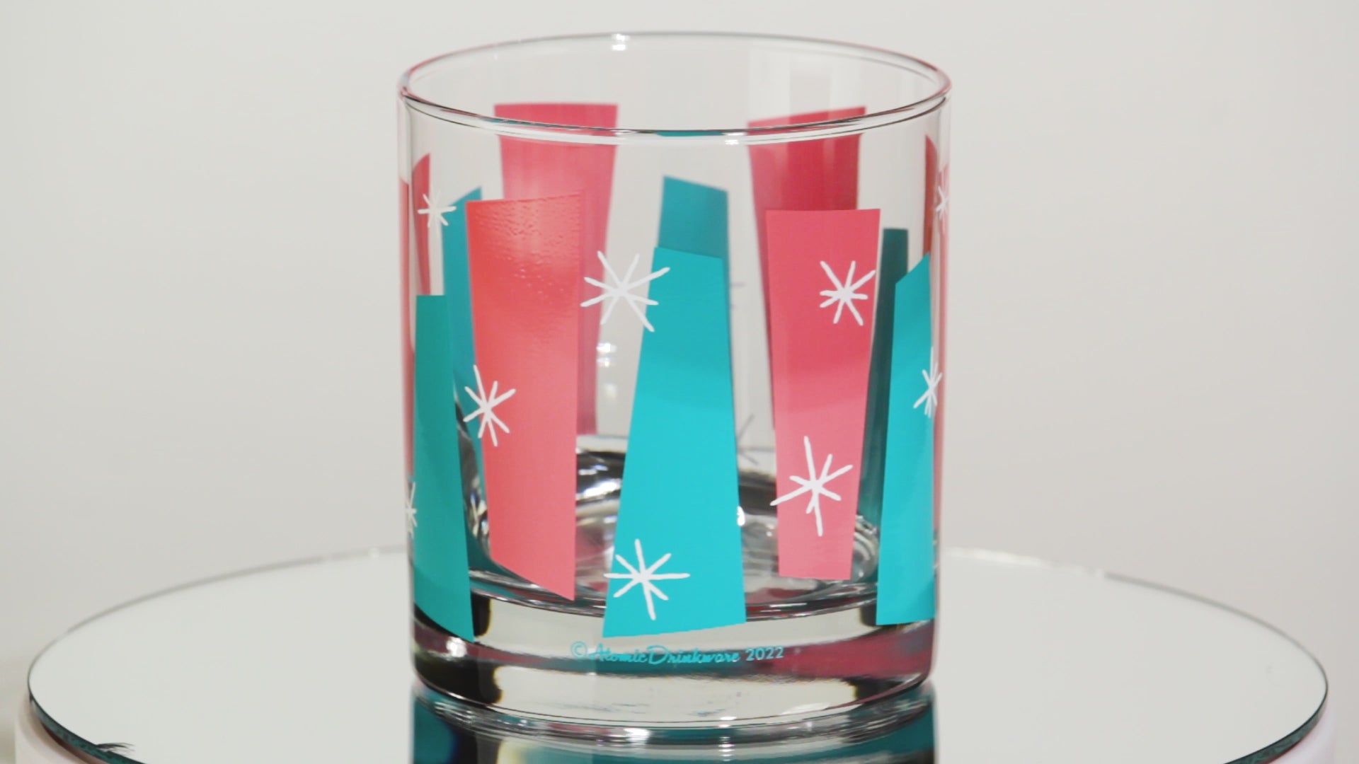 One glass tumblers with colorful retro geometric pattern on a white background