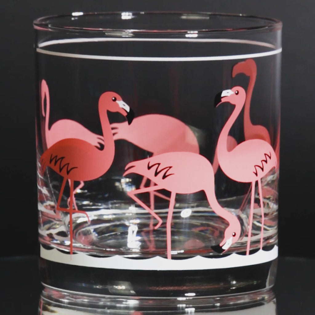 Clear glass tumbler with retro pink flamingo design on a white background